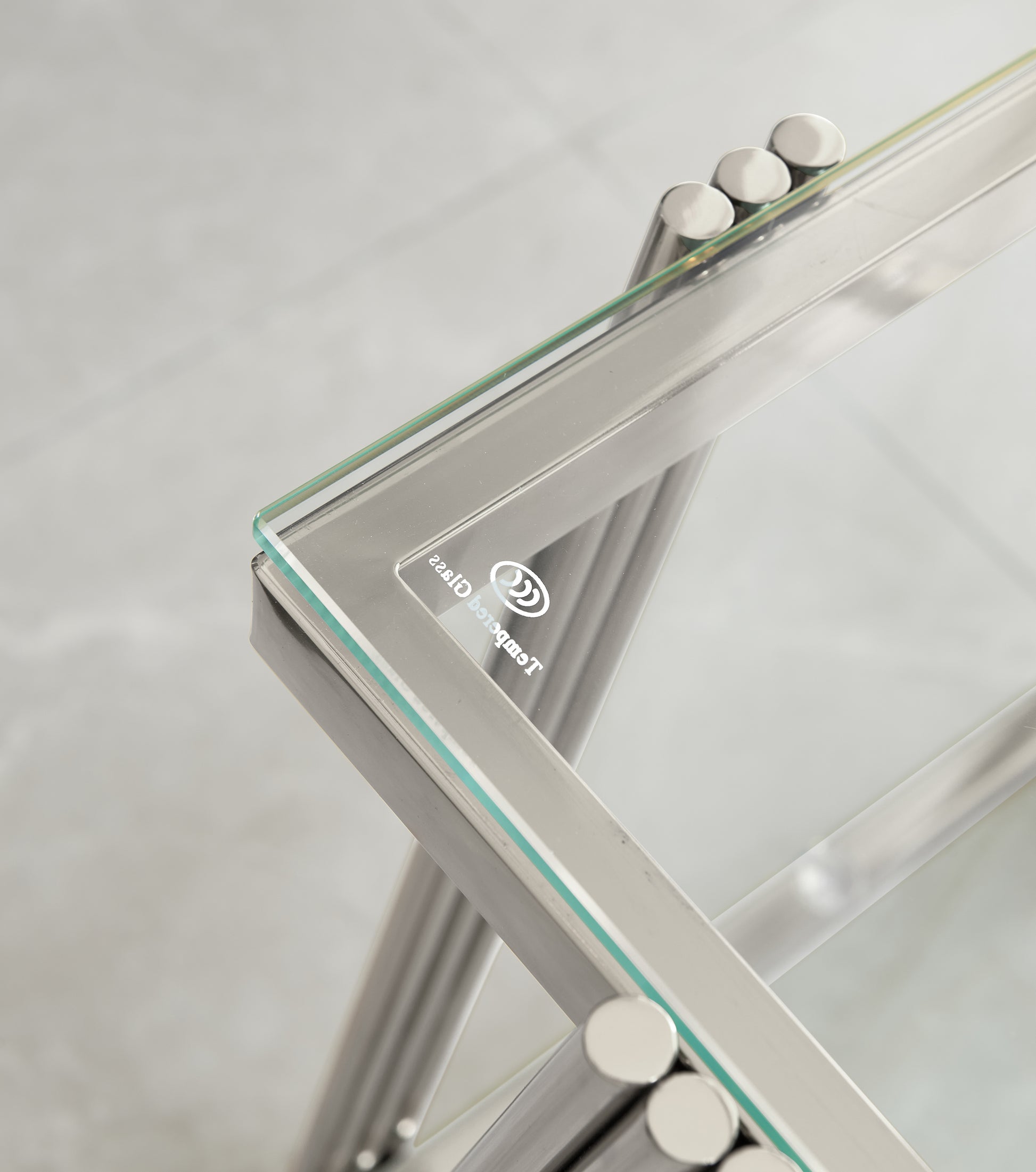 Closeup of a modern tempered glass coffee table with polished chrome legs