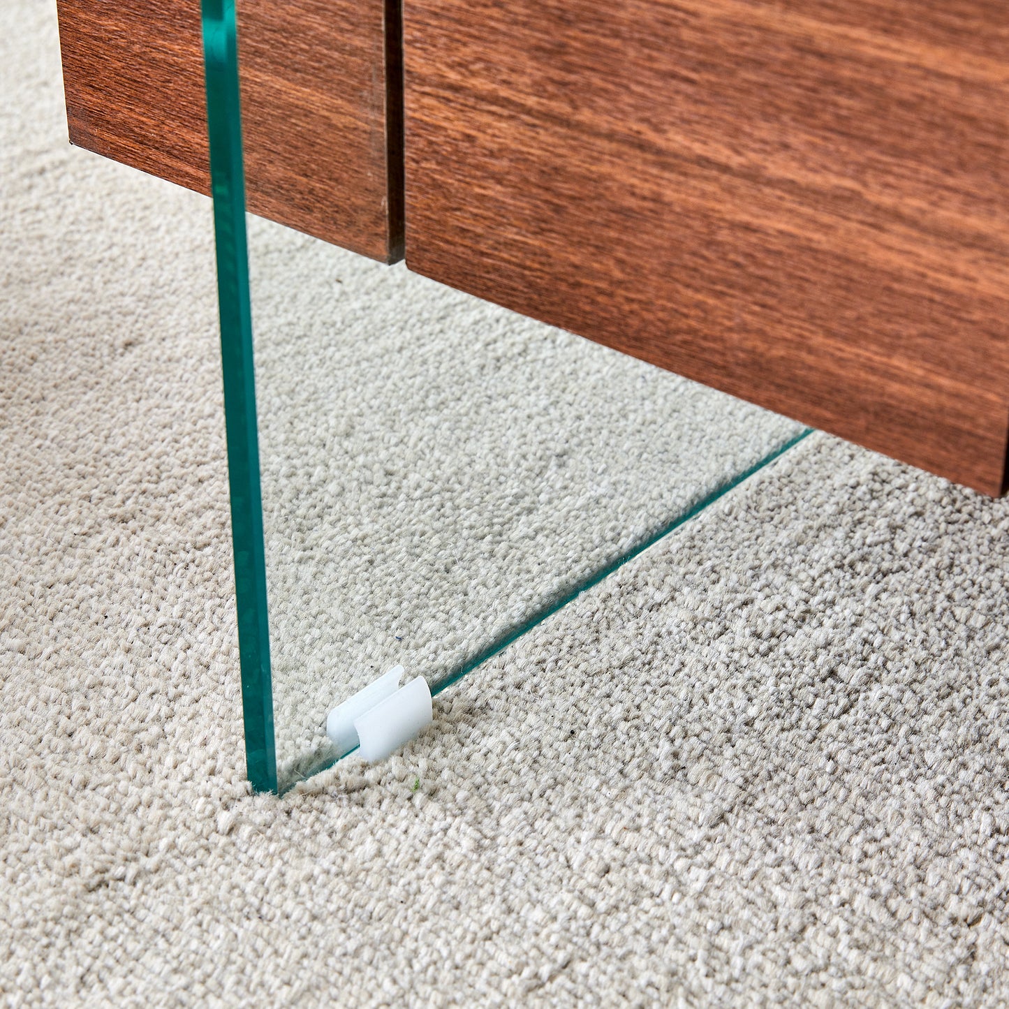 Closeup of a modern coffee table with a glass leg and wood top