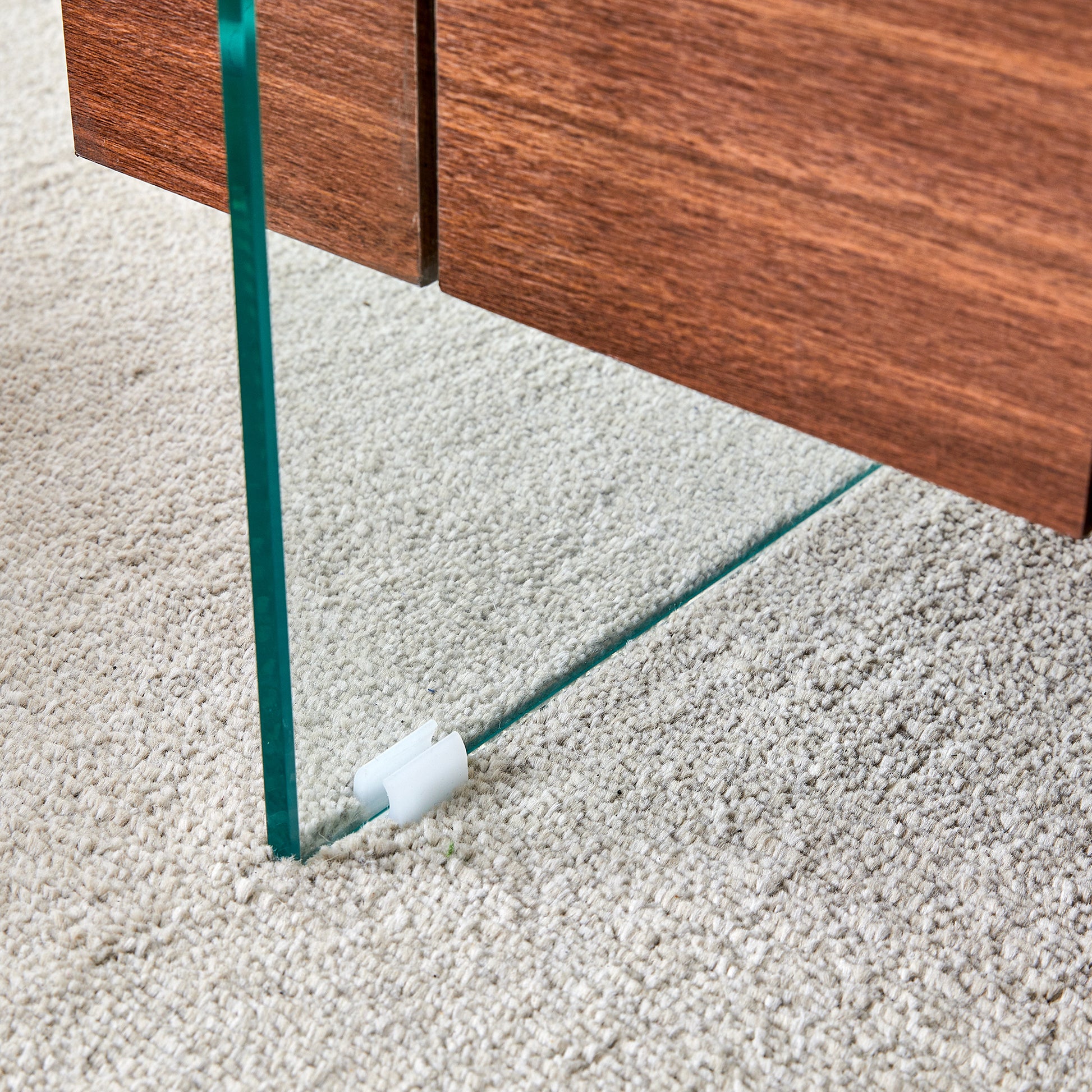 Closeup of a modern coffee table with a glass leg and wood top