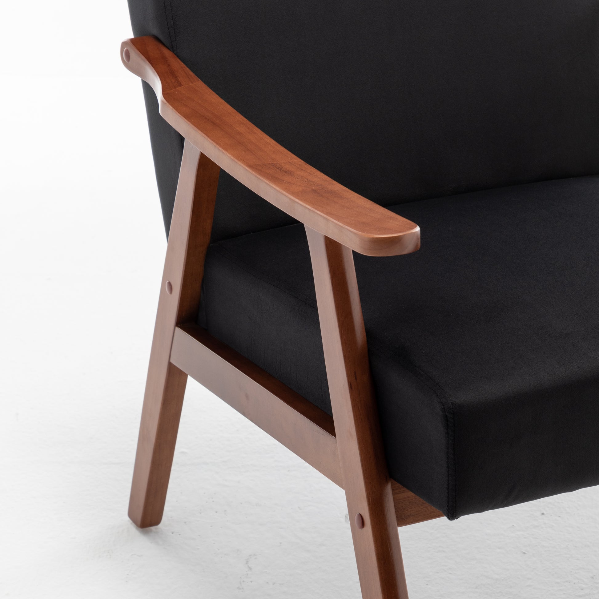 Close up of black upholstered armchair with curved wooden armrest and legs