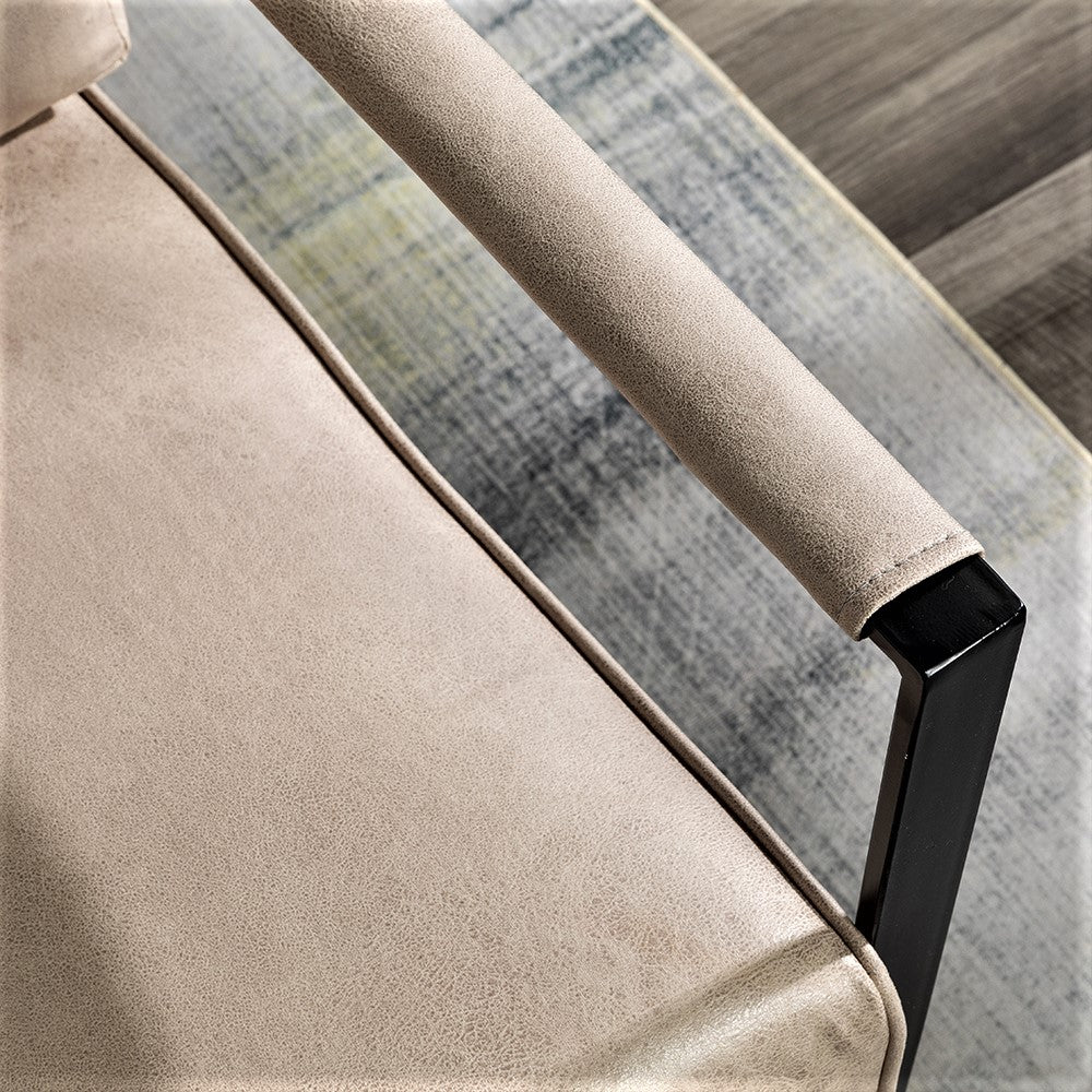 Closeup of beige upholstered armchair armrest with black metal frame leg
