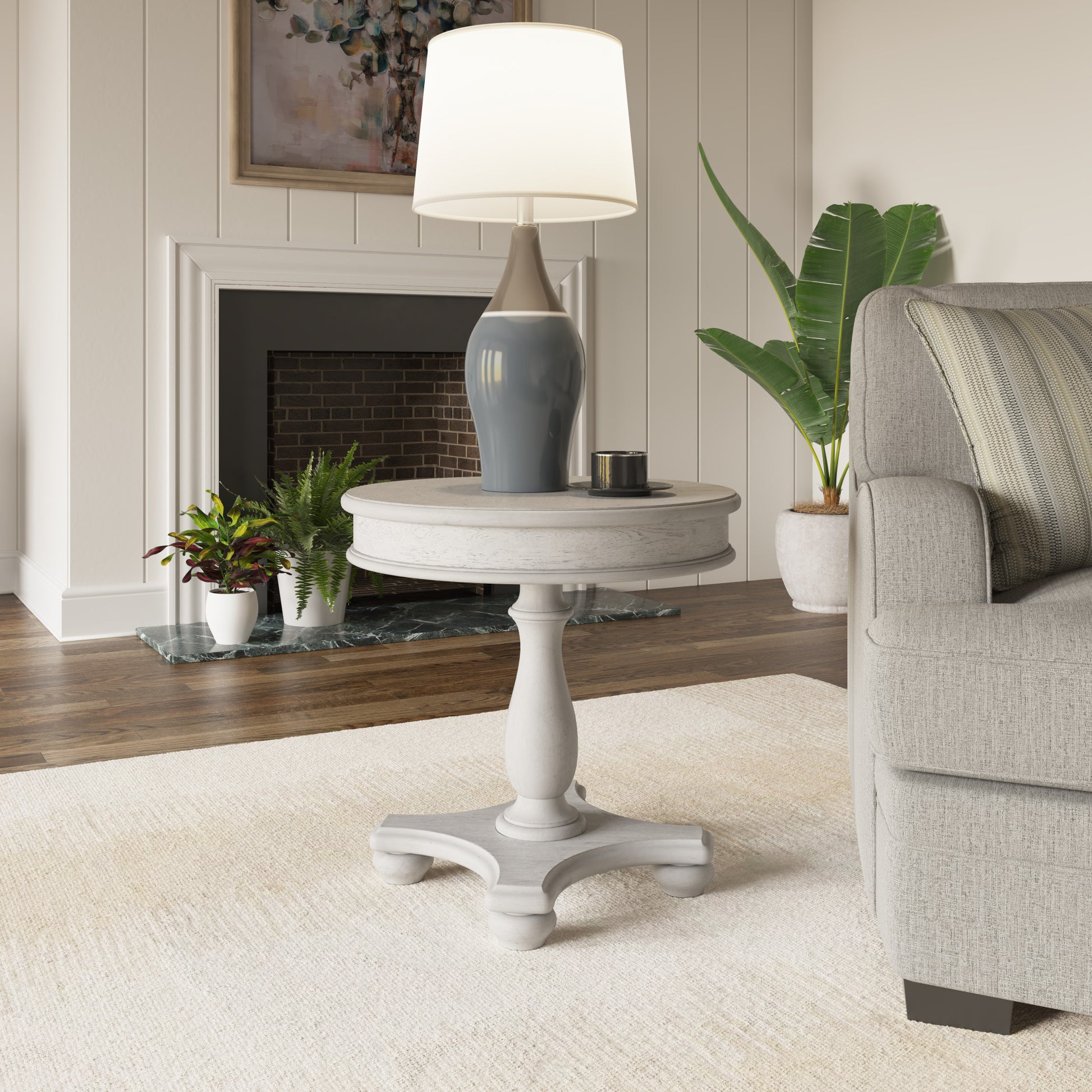 White distressed pedestal accent table with a round top