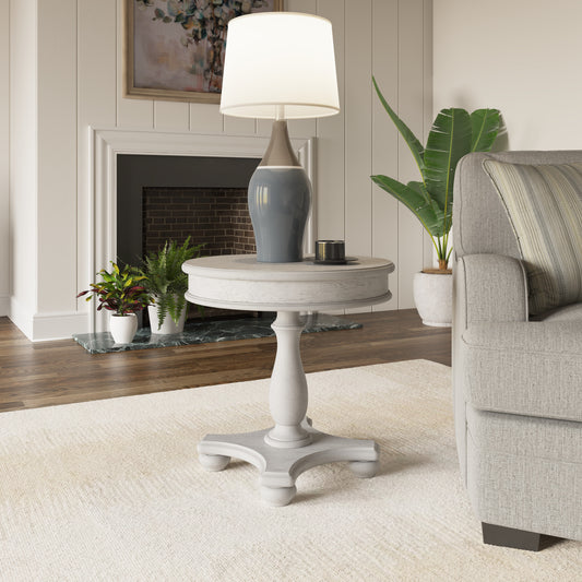 White distressed pedestal accent table with a round top
