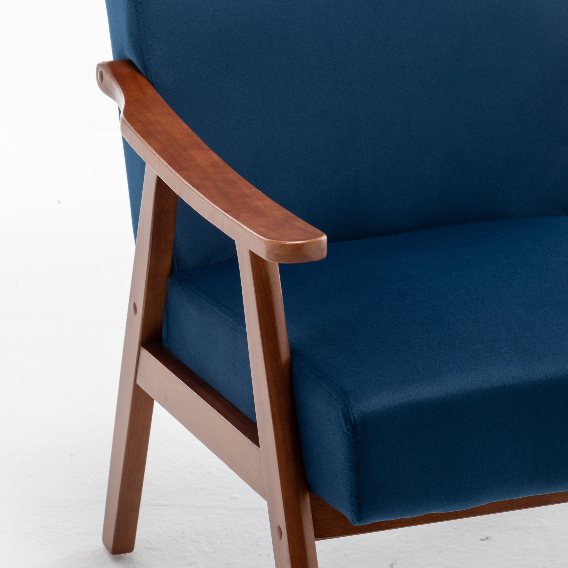 Closeup of a navy blue armchair with smooth wooden arms and legs