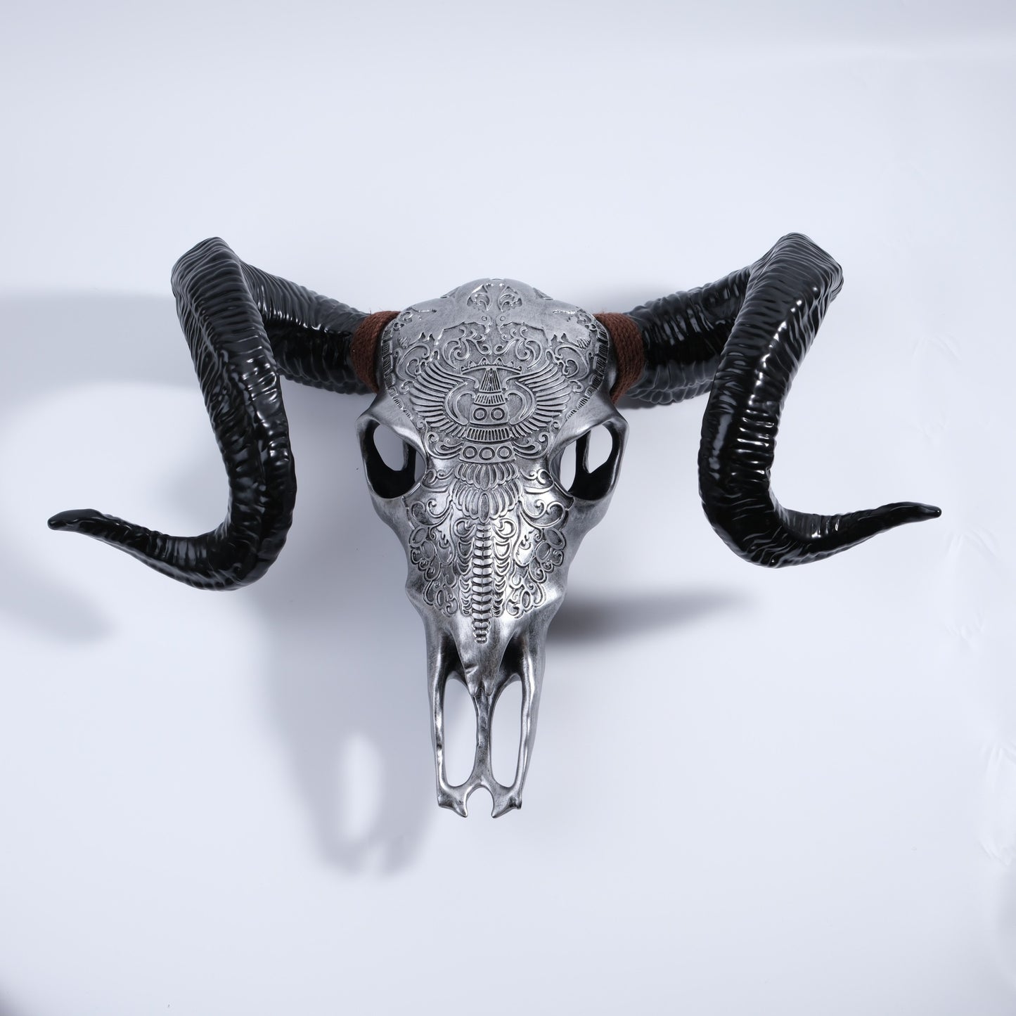 Ornate silver steer skull with curled black horns and brown twine accent