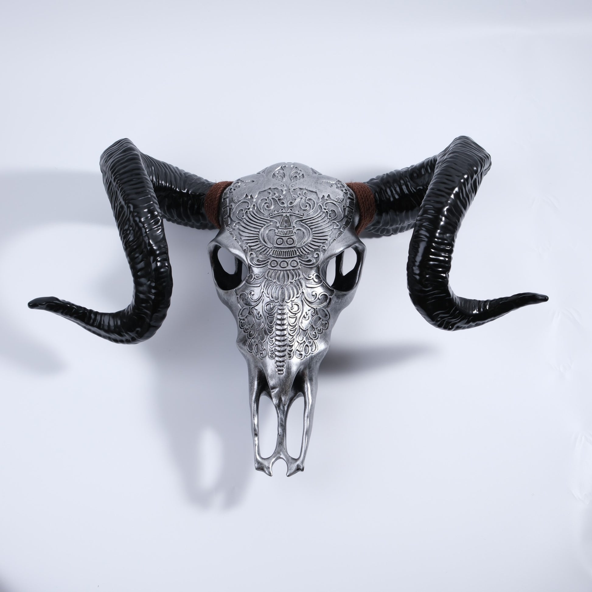 Ornate silver steer skull with curled black horns and brown twine accent