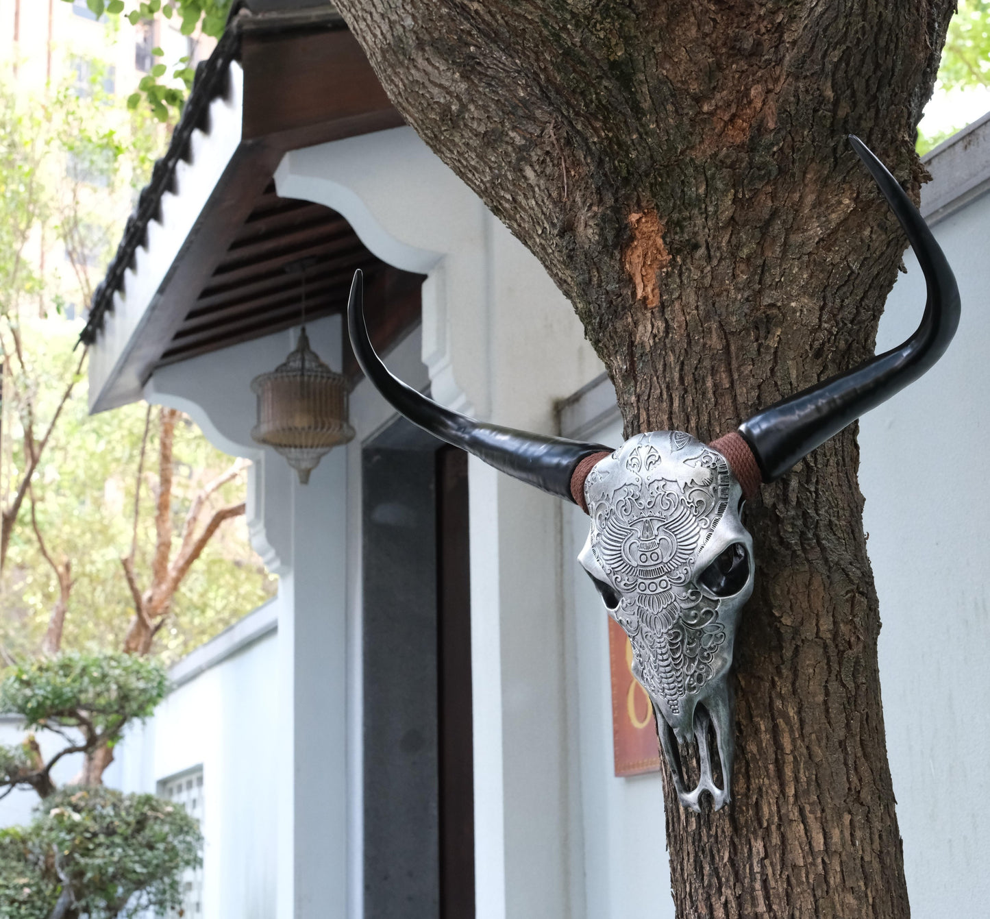 Ornate silver bull skull wall decor with black horns on tree