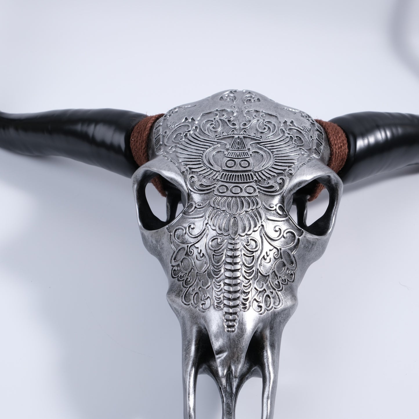 Decorative faux bull skull with intricate silver embossed patterns and black horns