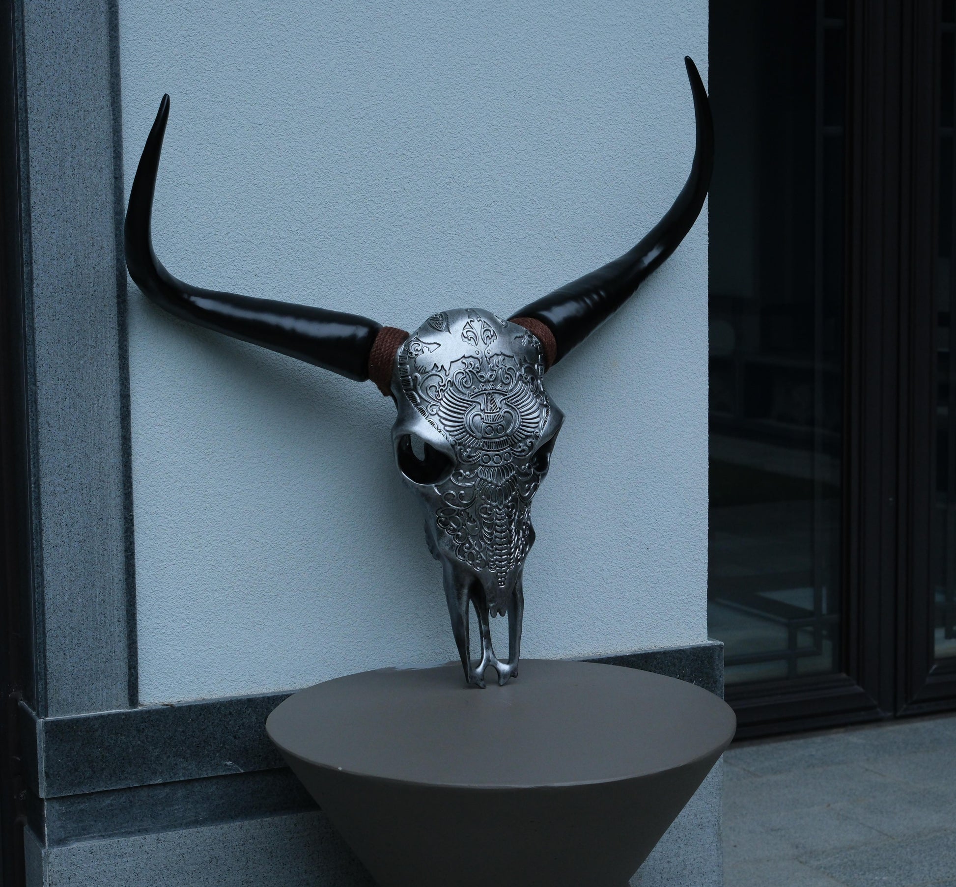 Ornate silver bull skull with black horns and intricate tribal carvings a statement decor piece