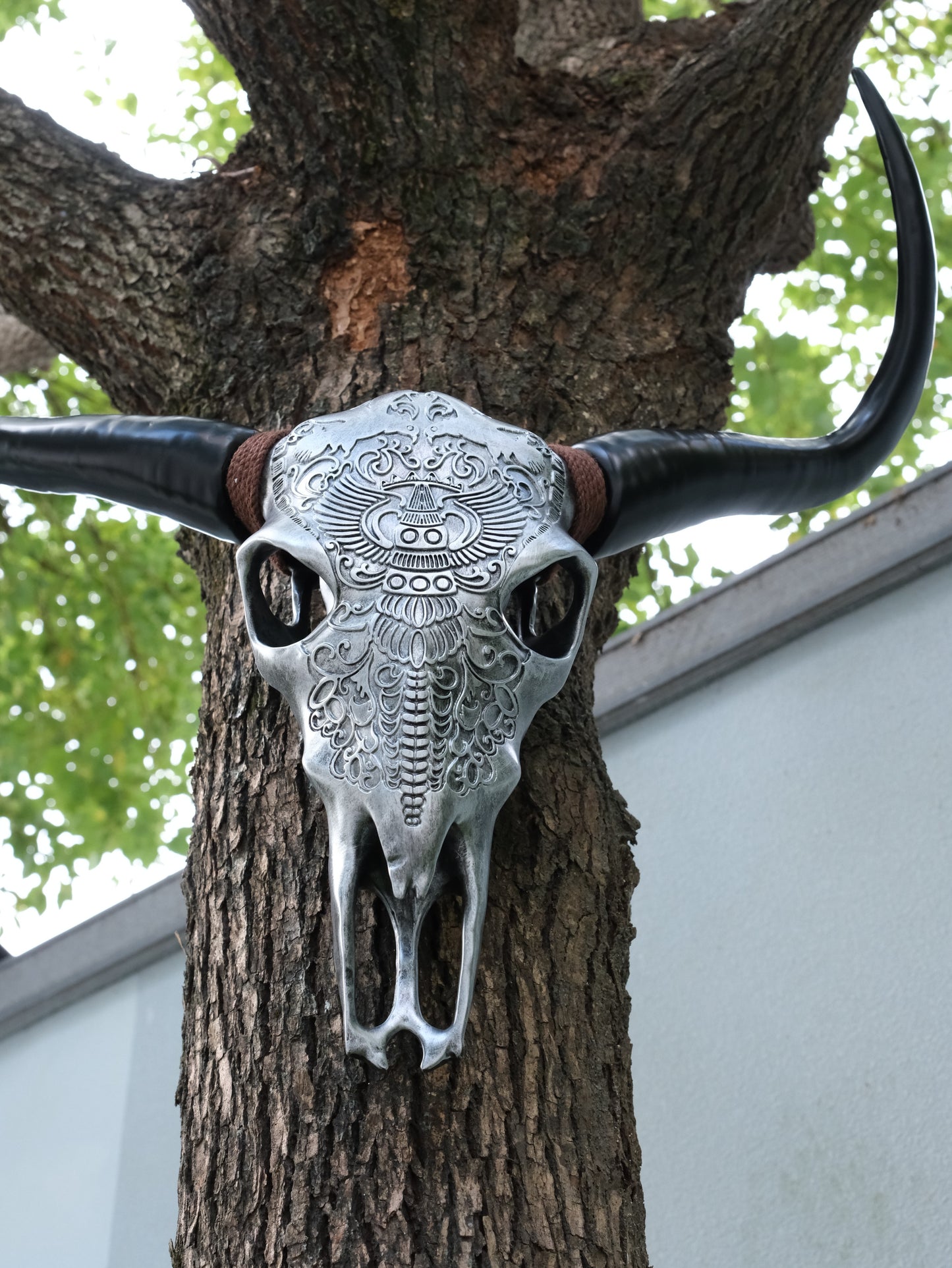 Silver faux bull skull with intricate tribal carvings and dark horns