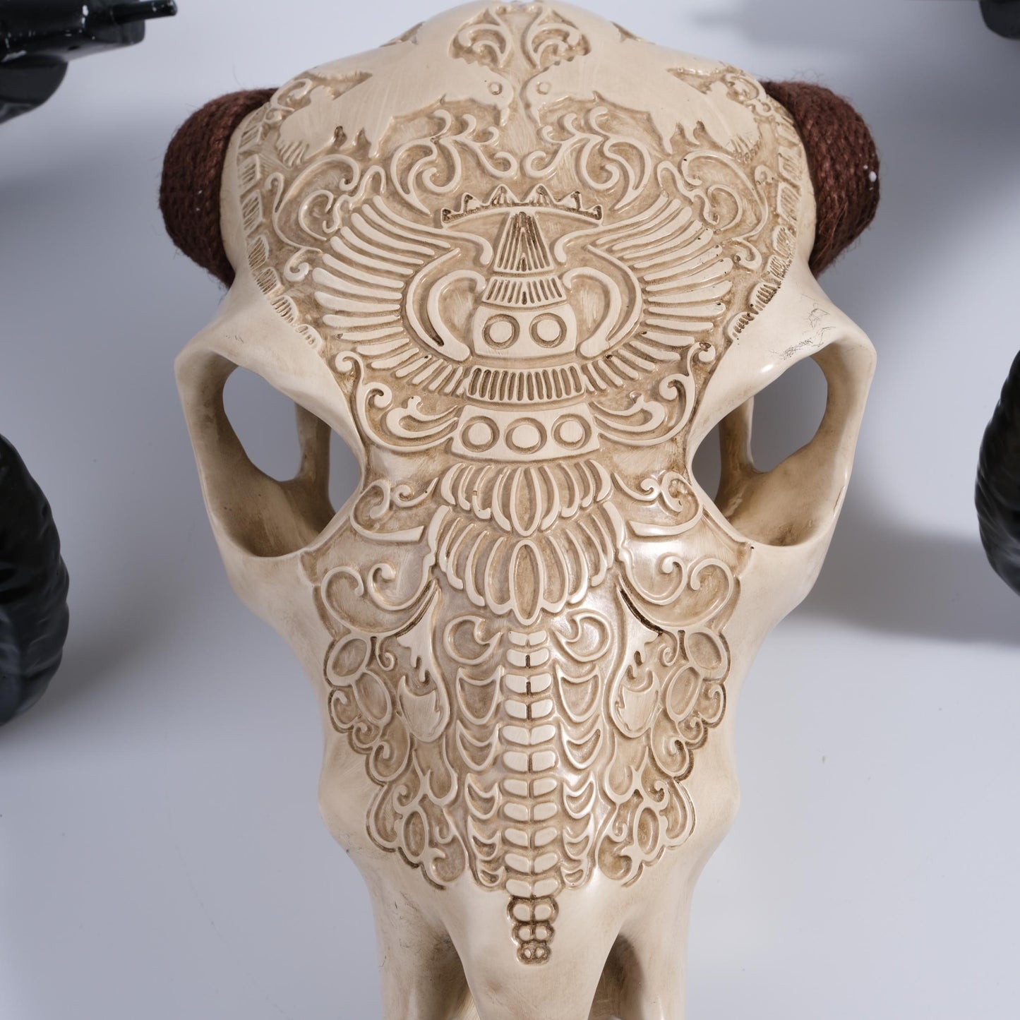 Ornate carved resin bull skull replica with braided horn accents tribal decor