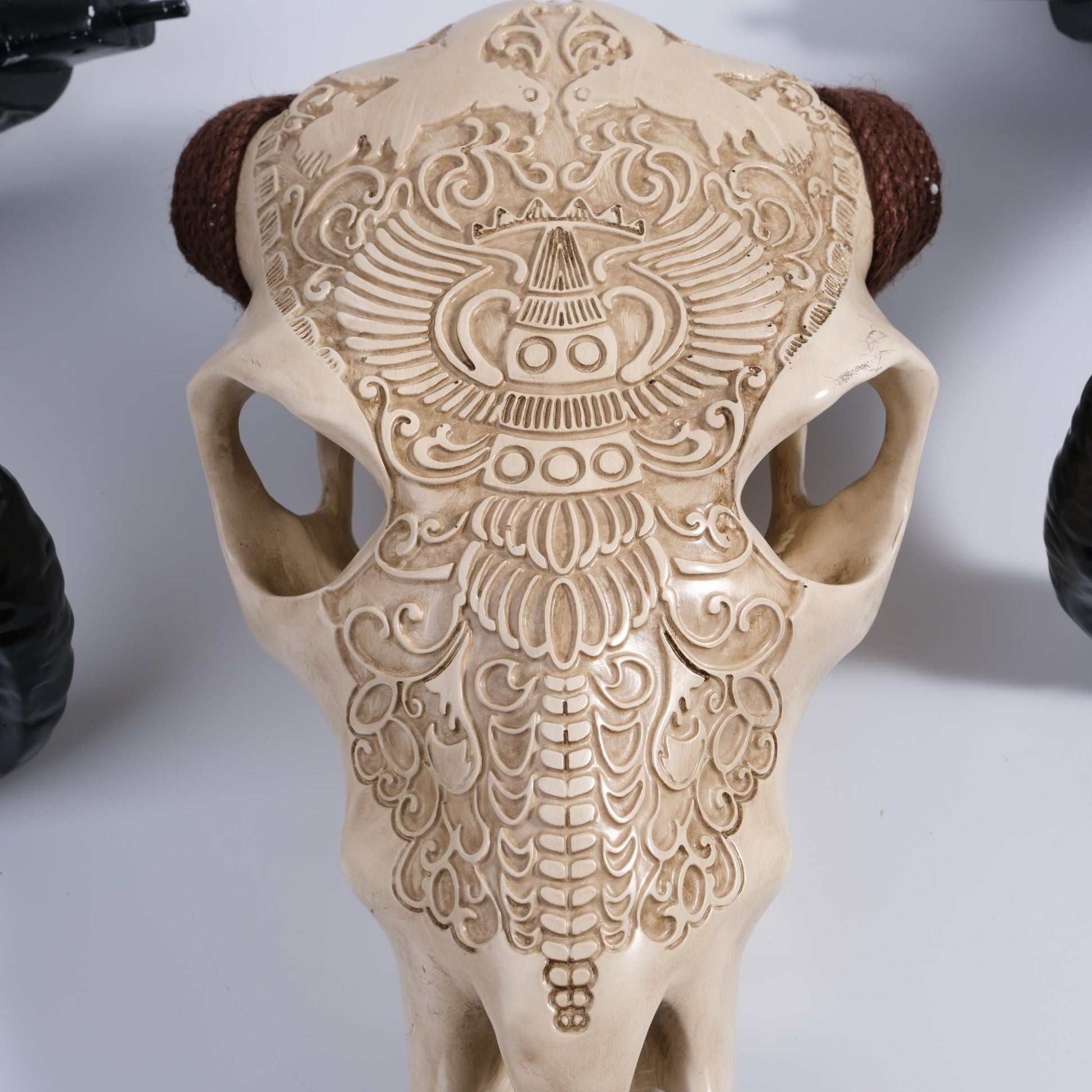 Ornate carved resin bull skull replica with braided horn accents tribal decor