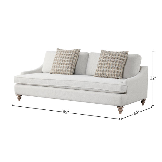 Light gray textured fabric sofa with patterned accent pillows and turned wooden legs