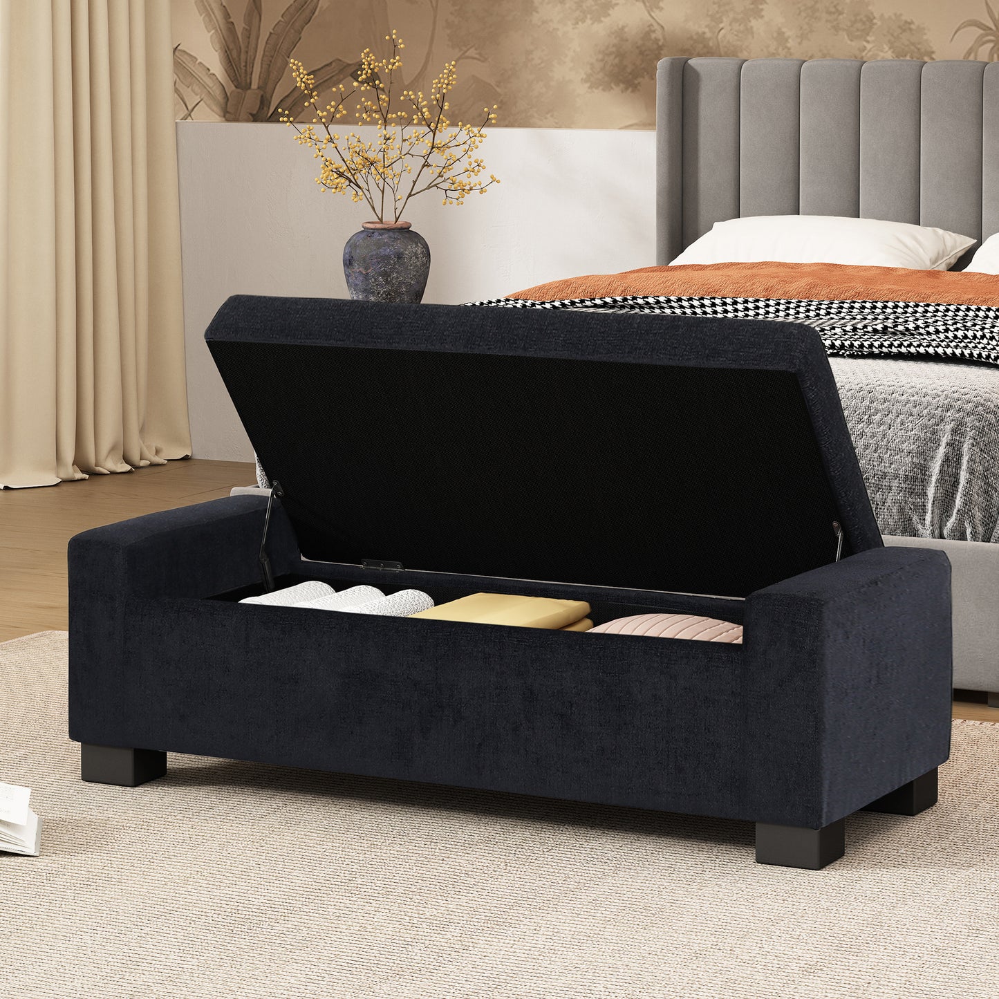 Dark blue upholstered storage bench with open lid revealing storage items inside