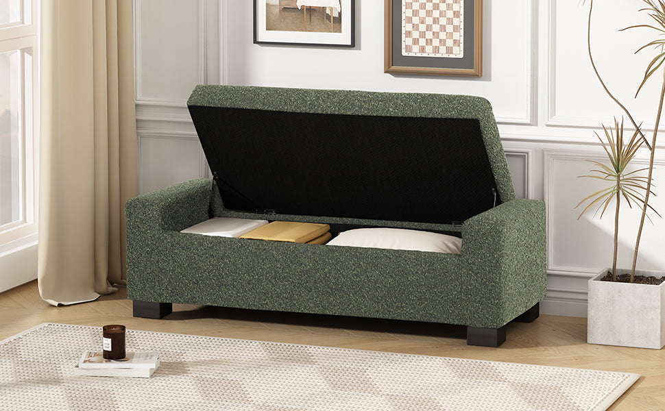 Green upholstered storage bench with lid open revealing pillows and blankets