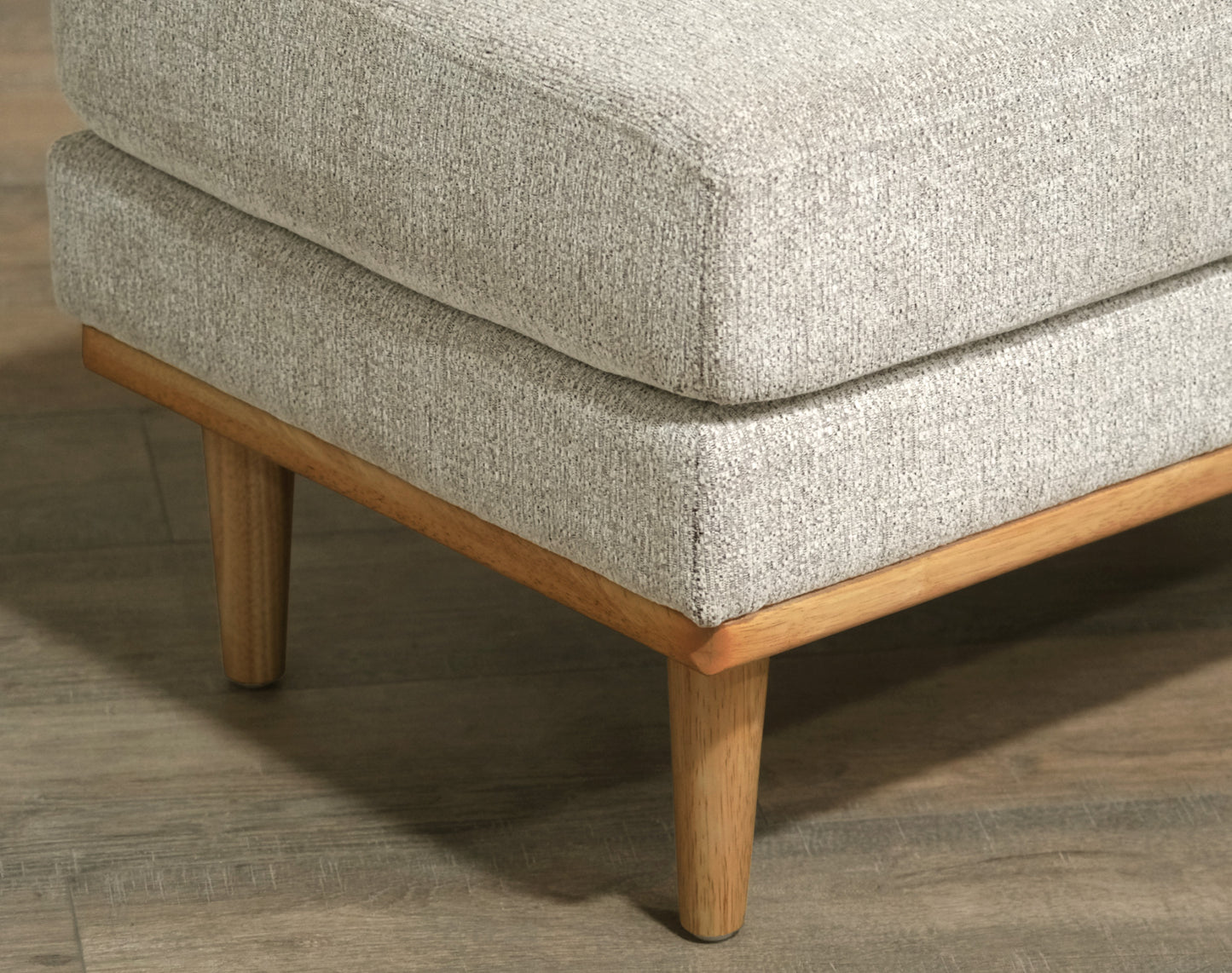 Textured grey fabric ottoman with tapered wooden legs and a light wood frame
