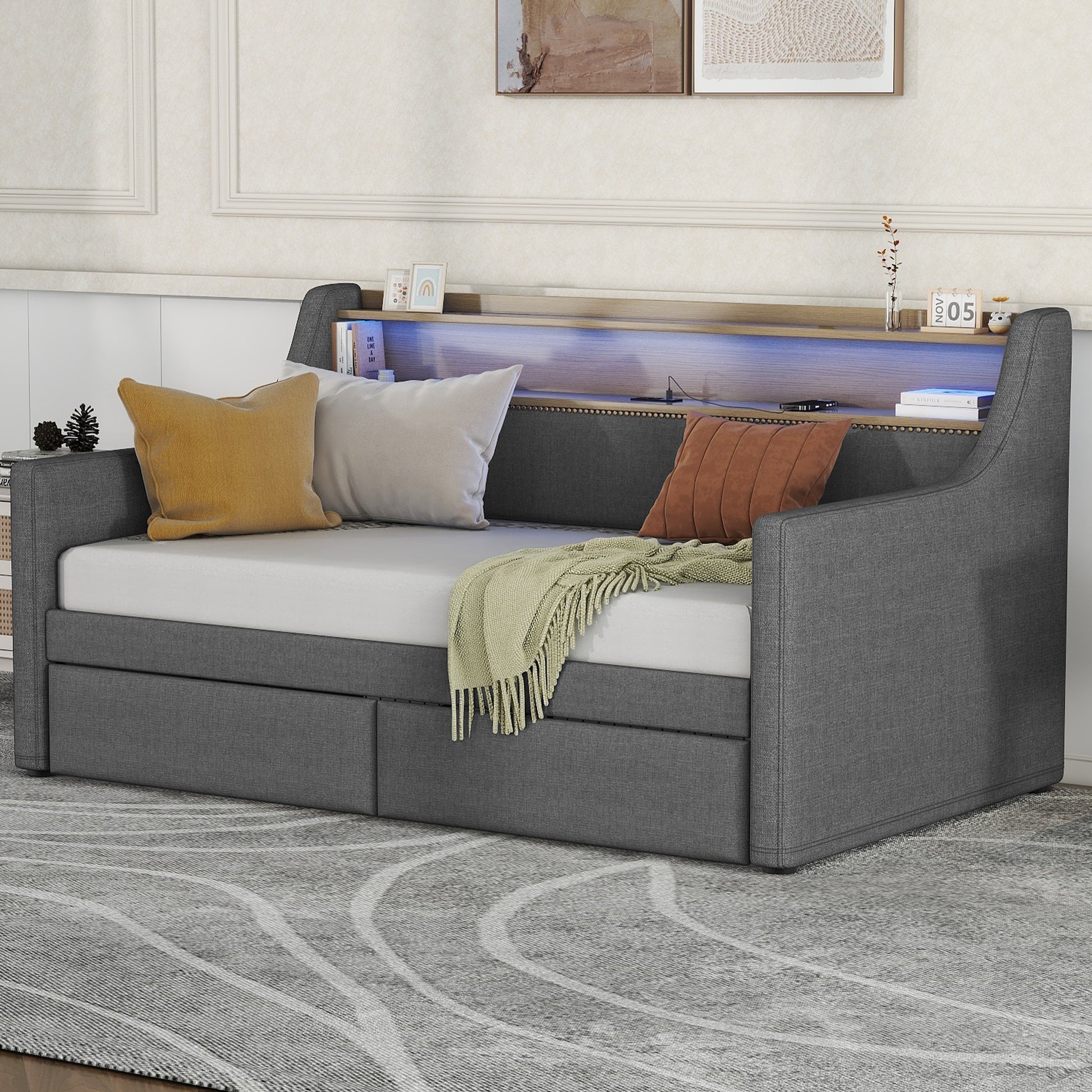 Grey upholstered daybed with builtin storage drawers and a lighted shelf