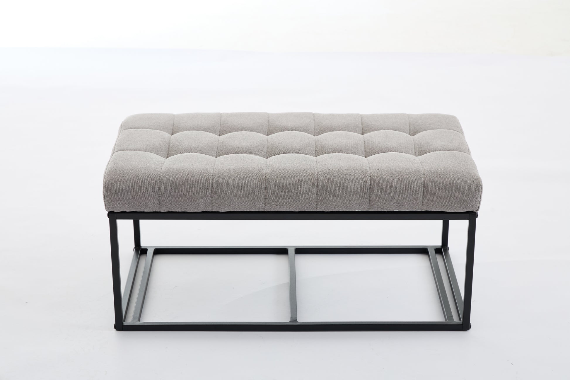 Tufted grey fabric ottoman with black metal frame and legs