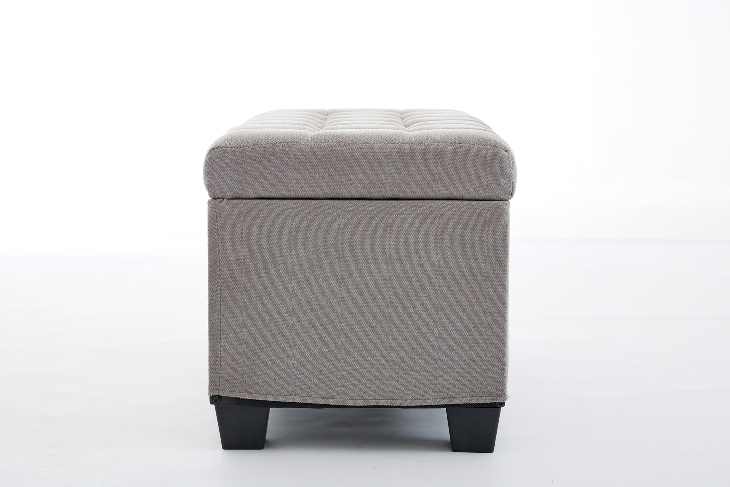 Gray fabric storage ottoman with tufted lid and black legs