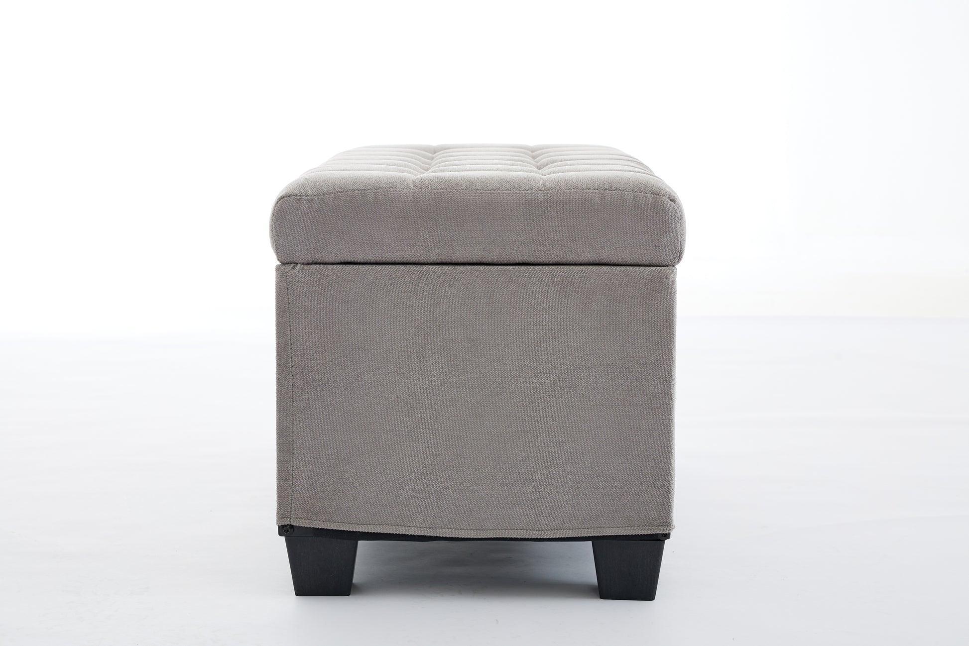 Gray fabric storage ottoman with tufted lid and black legs