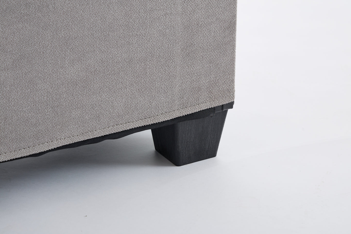 Textured grey fabric upholstery with a dark wooden furniture leg