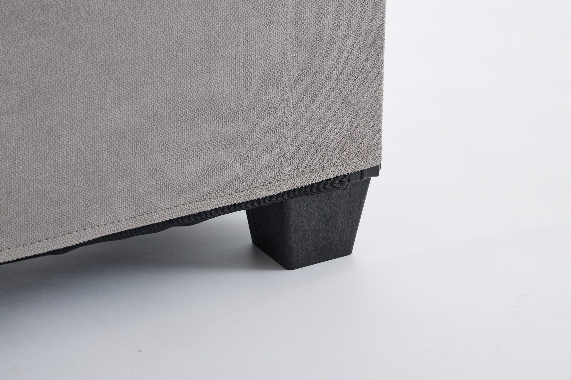 Textured grey fabric upholstery with a dark wooden furniture leg