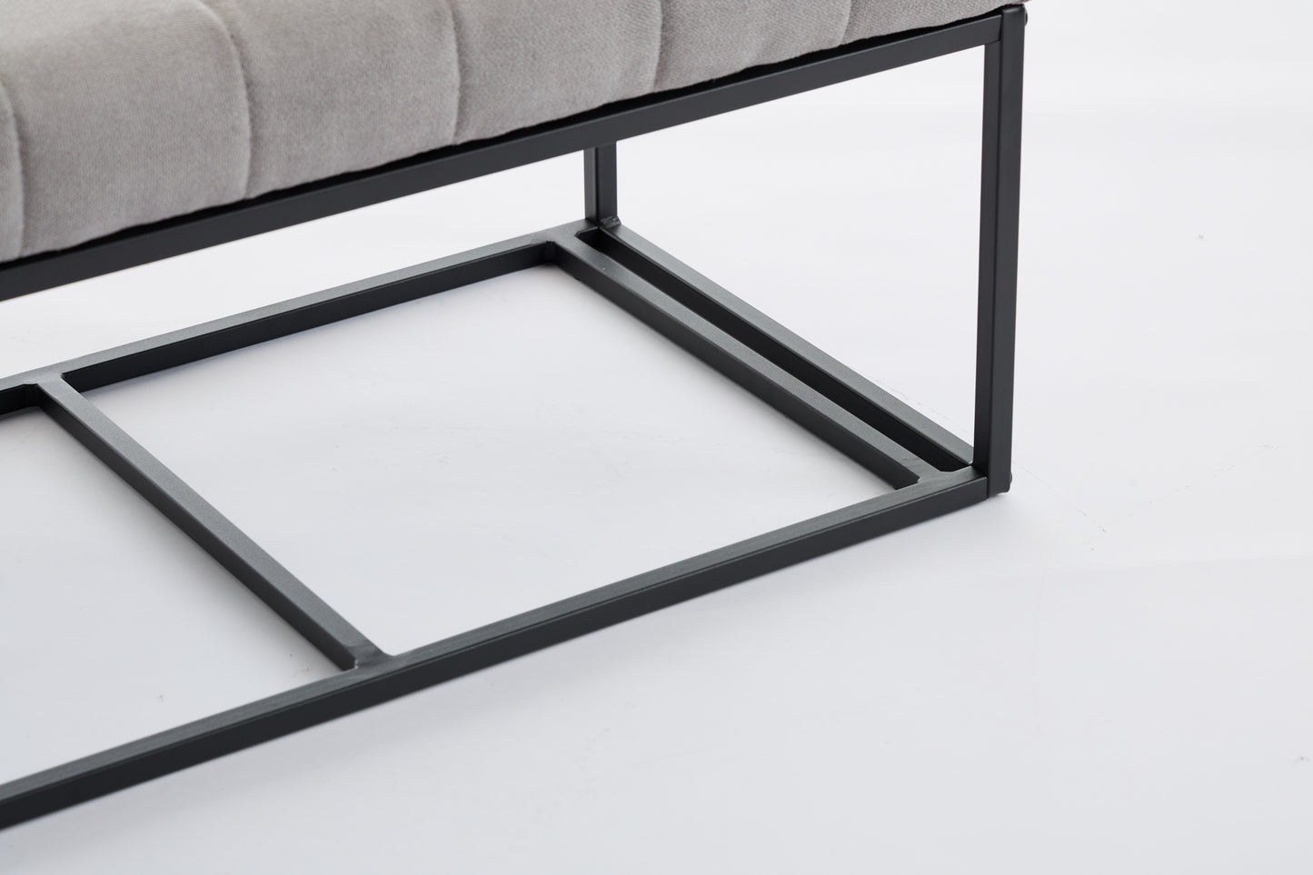Closeup of a grey upholstered bench with a black metal frame and tufted detail