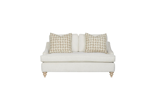 Cream boucle loveseat with geometric patterned accent pillows and turned wooden legs modern farmhouse style