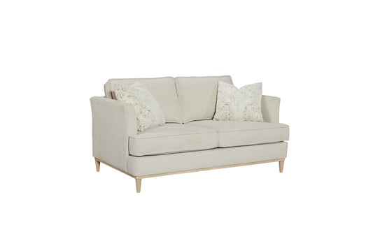 Beige fabric twoseater sofa with patterned throw pillows and wooden legs
