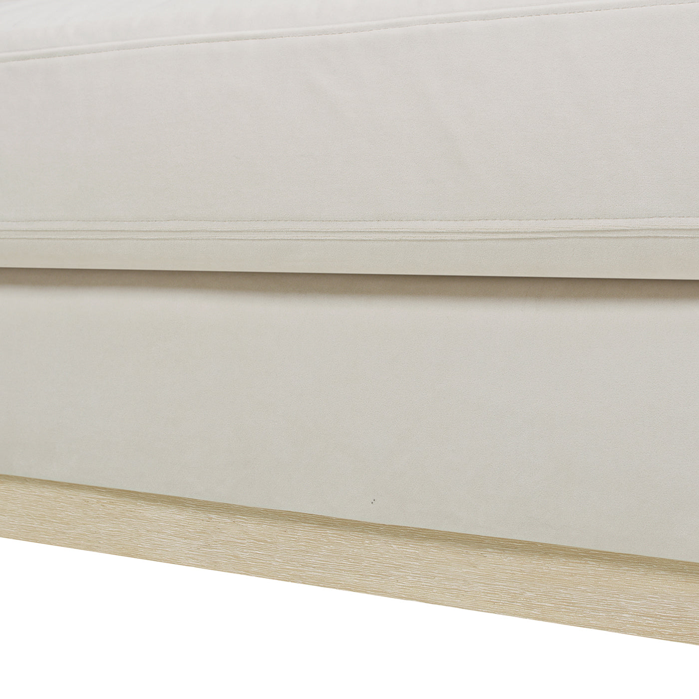 Cream upholstered sofa detail with stitched panel and light wood base
