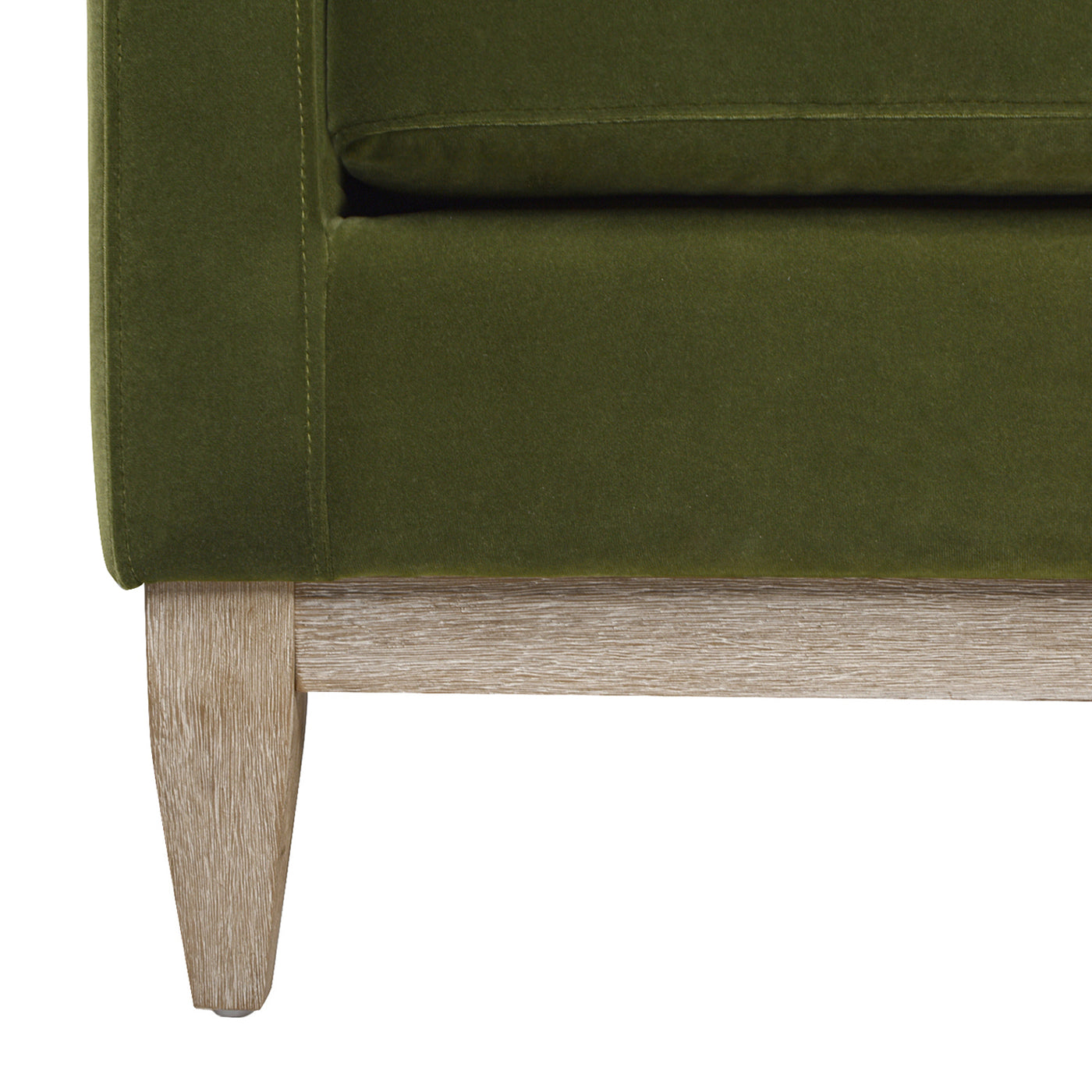 Closeup of a green velvet armchair base with a light wood leg