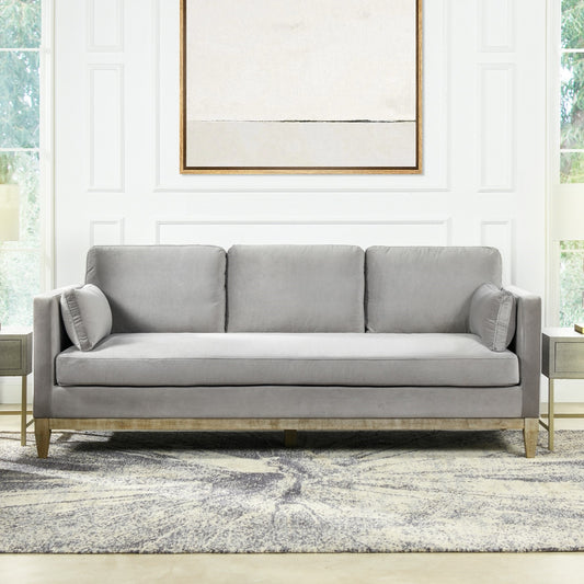 Gray velvet threeseater sofa with wooden base and matching throw pillows Accent piece for living room