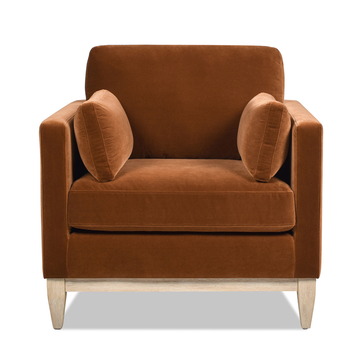 Brown velvet armchair with two accent pillows and light wood legs