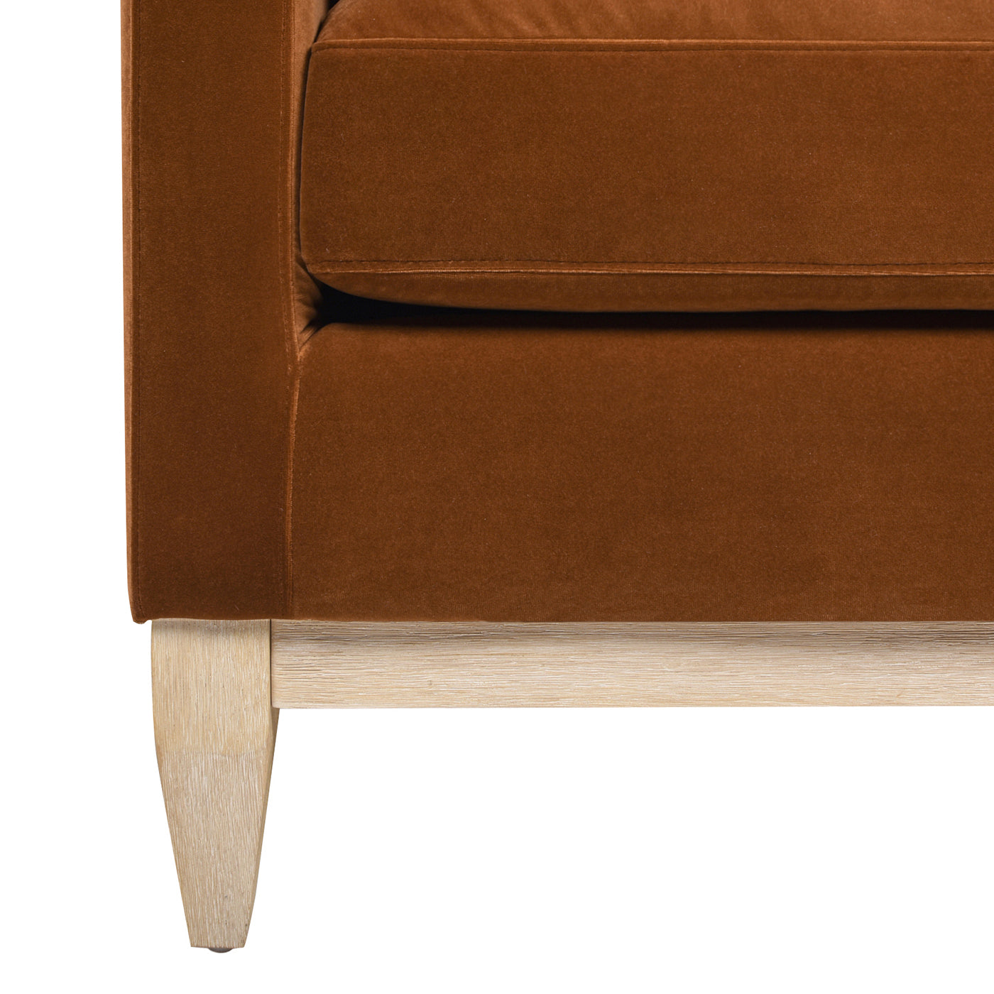 Closeup of a rich brown velvet sofa arm with a light wood base