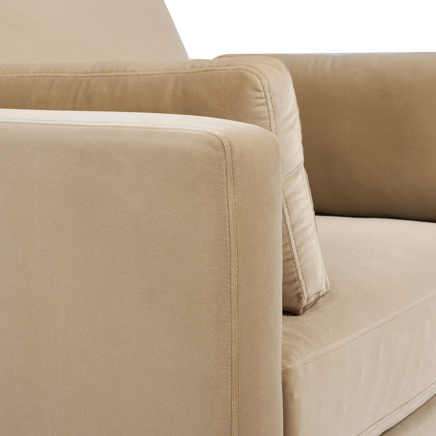 Closeup of plush beige velvet sofa armrest with detailed stitching and a matching cushion