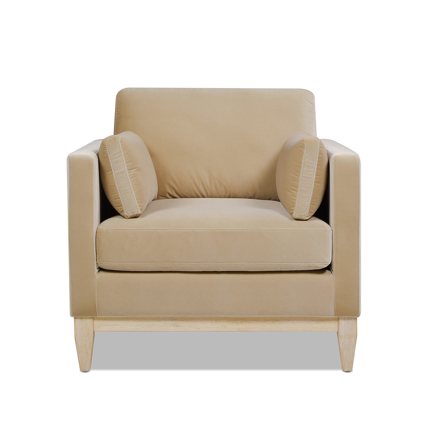 Tan velvet armchair with wooden legs and accent pillows