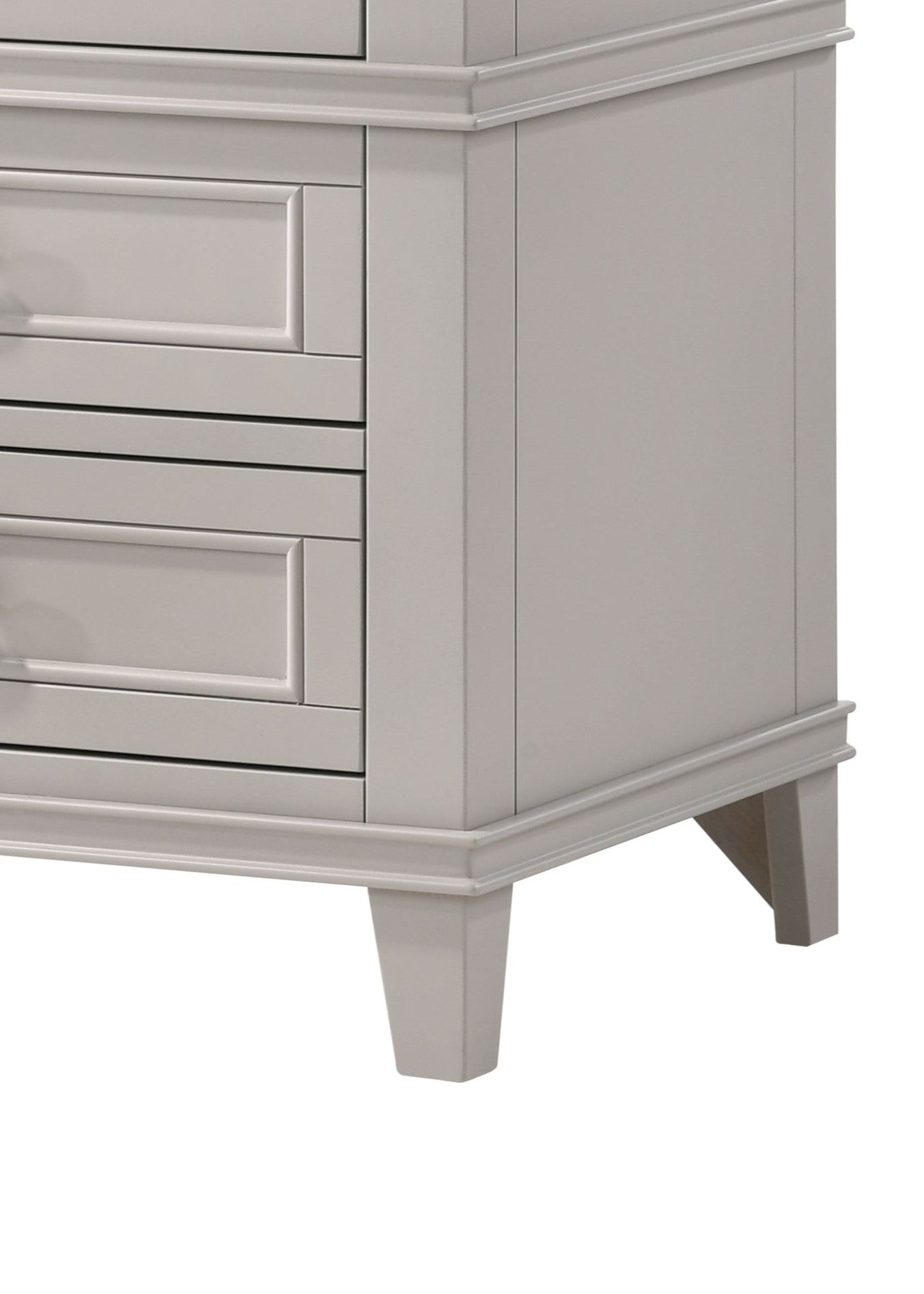 Closeup of a light gray dresser with recessed drawer fronts and ornate molding