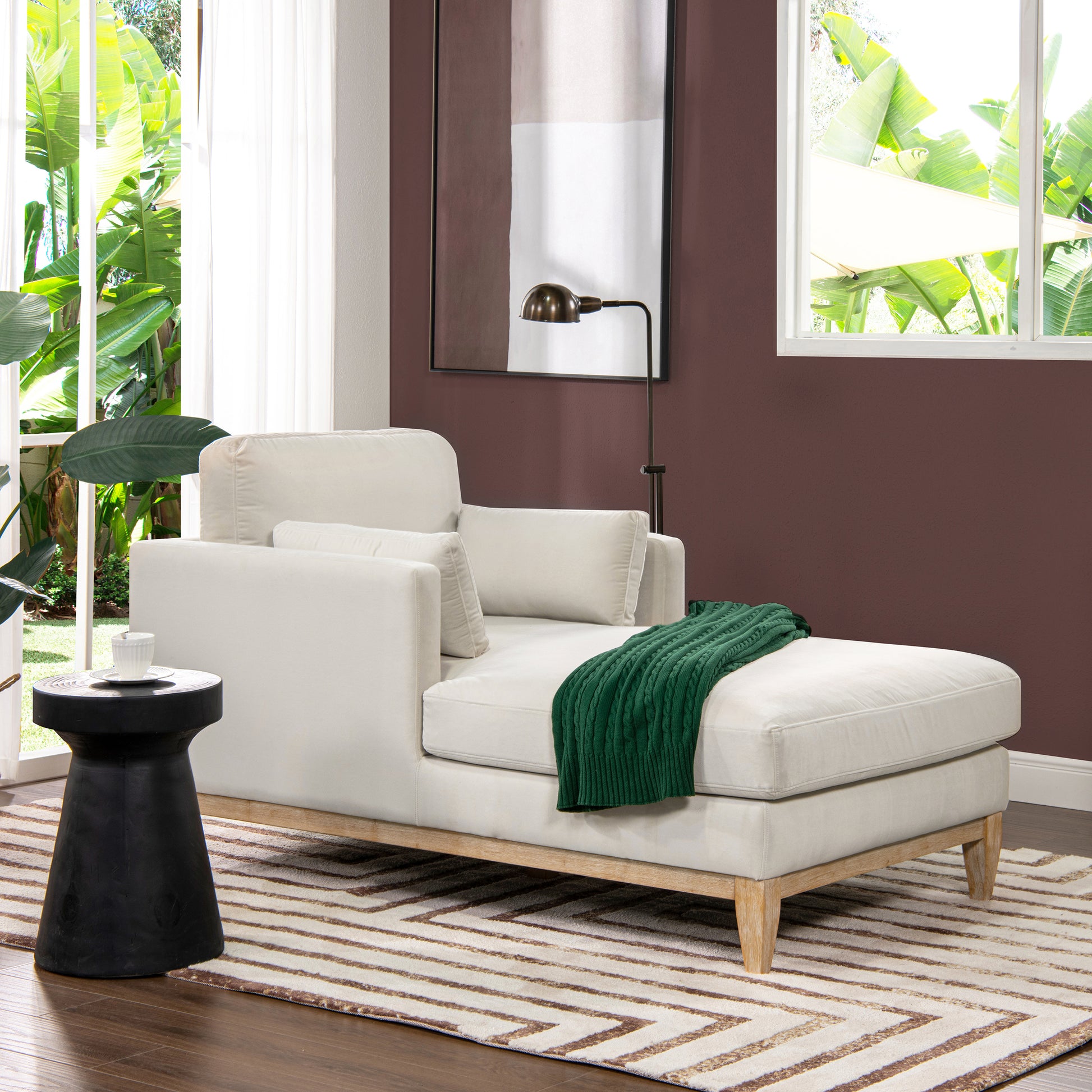 Cream fabric chaise lounge with green cable knit throw