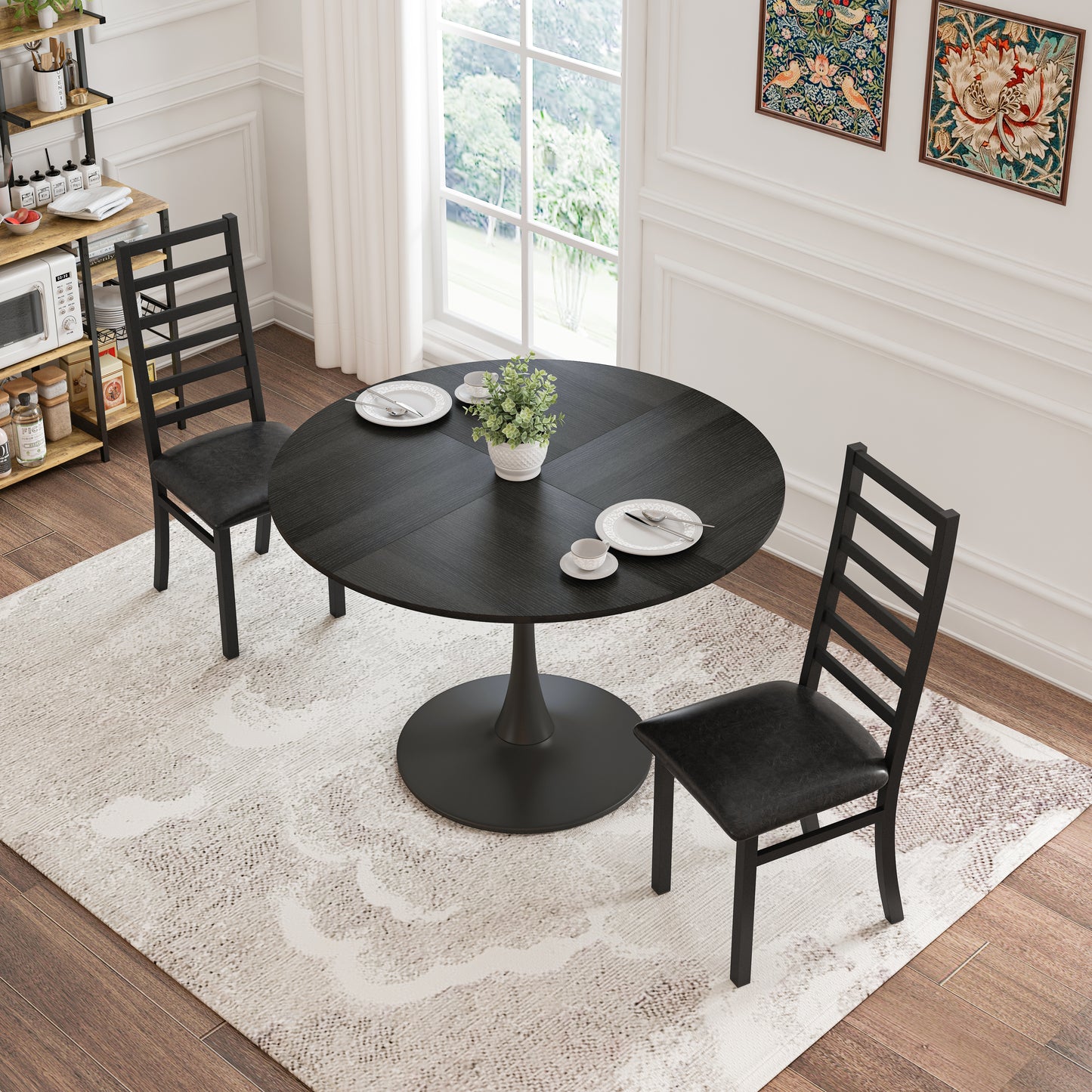 Black round pedestal dining table with two black ladderback chairs