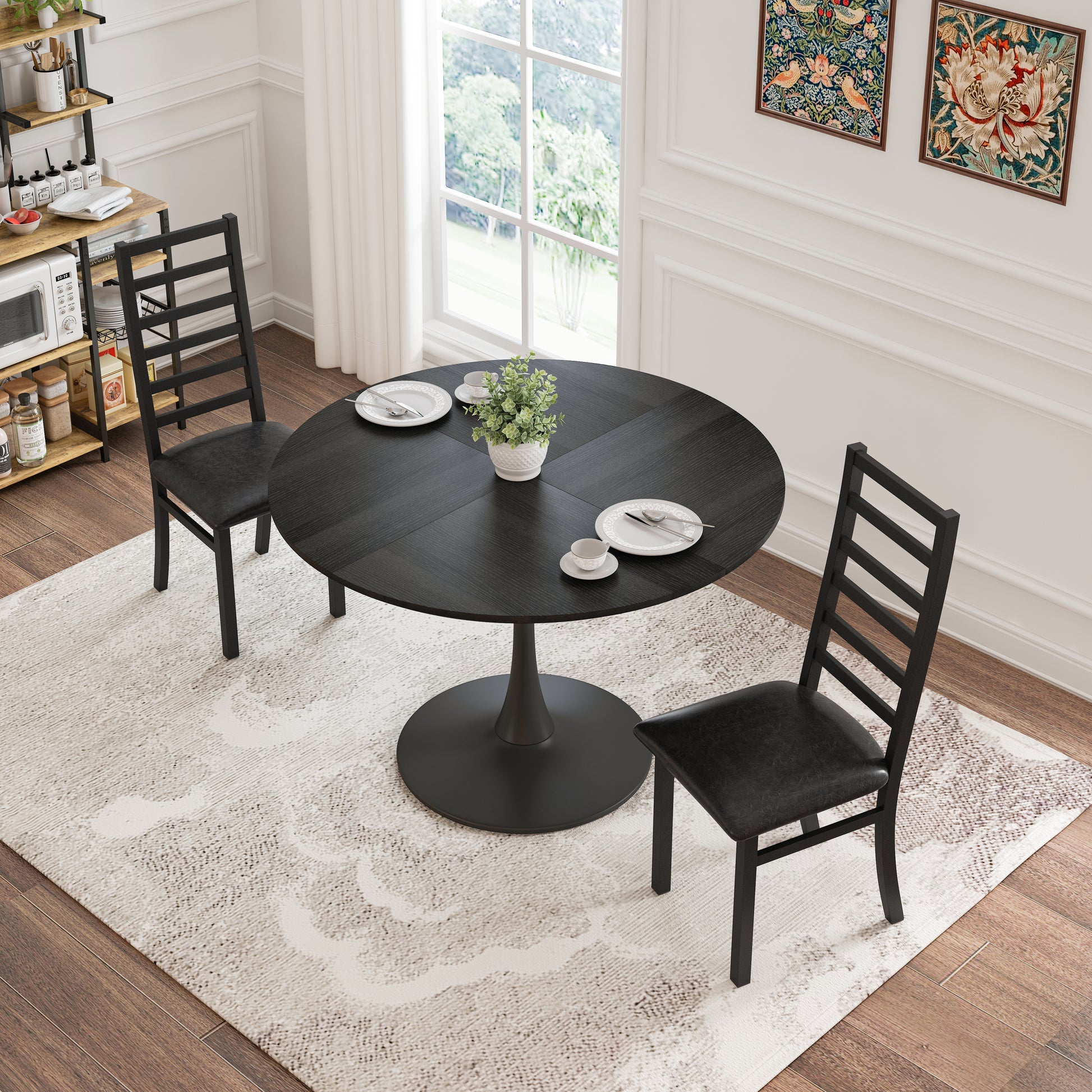 Black round pedestal dining table with two black ladderback chairs