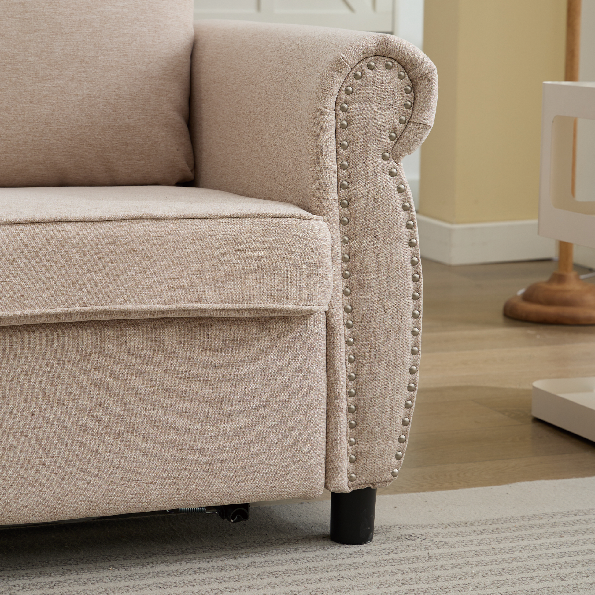Beige linen sofa armrest with decorative nailhead trim and plush cushion