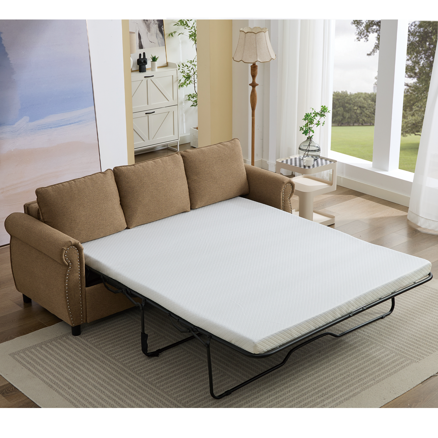 Tan linen sofa bed with studded arms unfolded to reveal a white mattress for sleeping