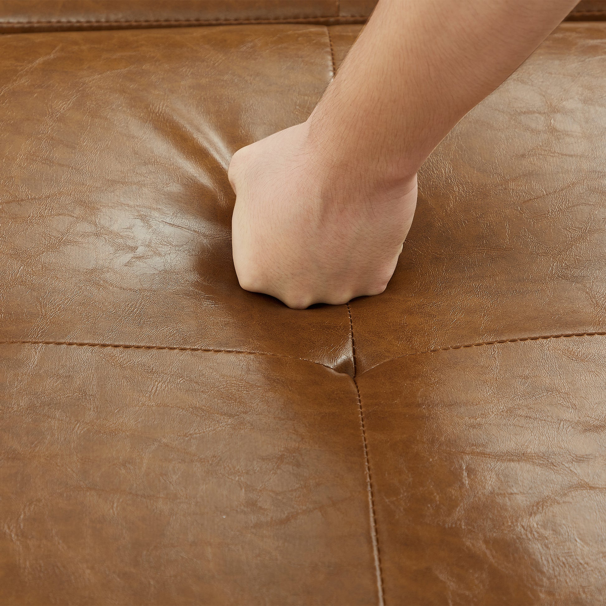 Close up of brown faux leather couch with tufted detailing