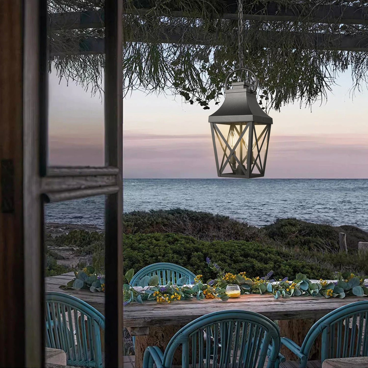 Black metal outdoor lantern with glass panes suspended from a chain evokes coastal charm