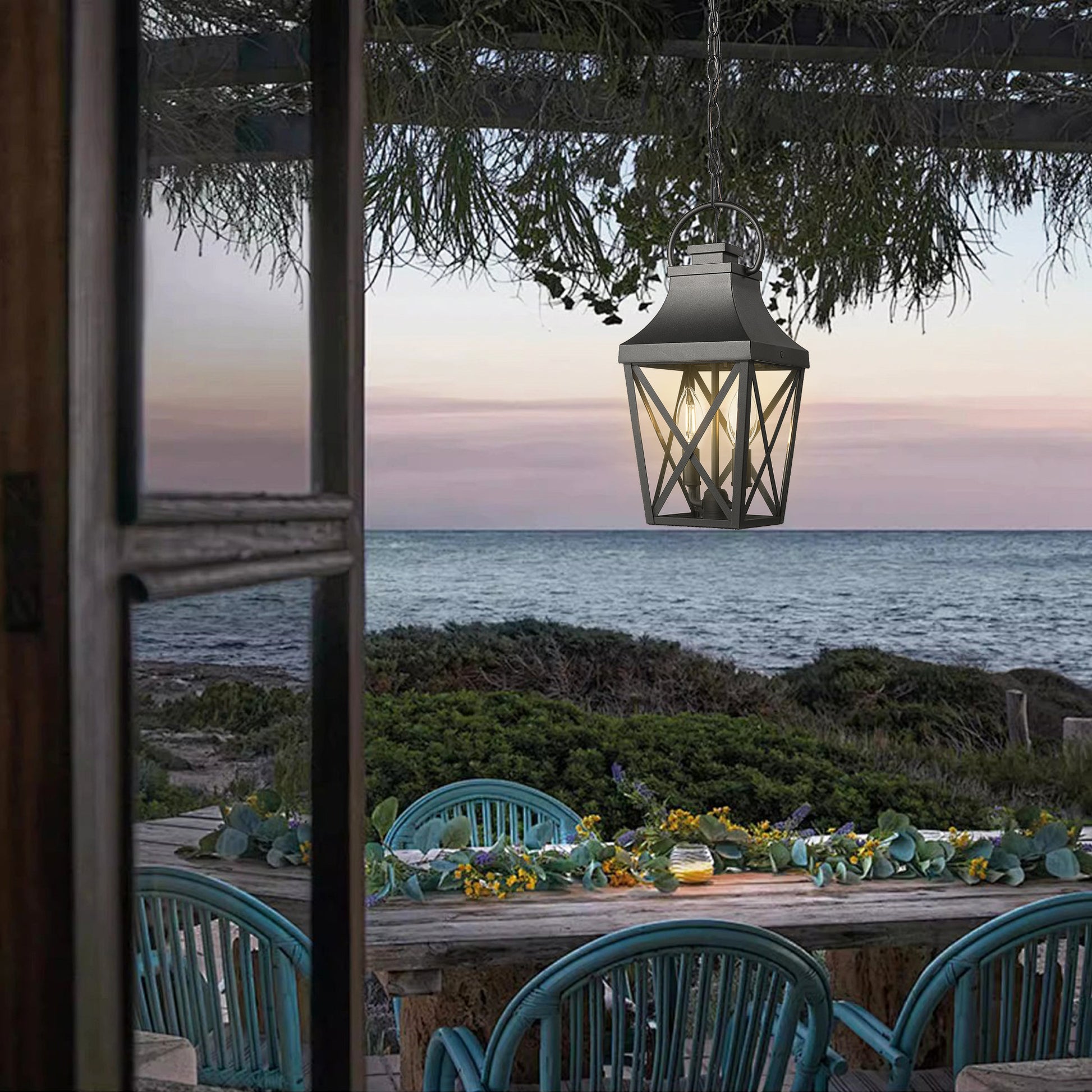 Black metal outdoor lantern with glass panes suspended from a chain evokes coastal charm