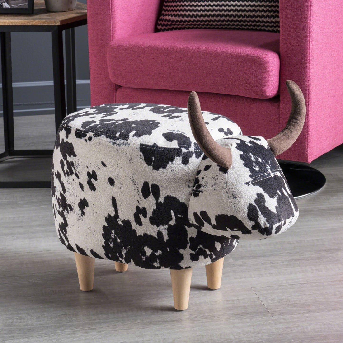 Cow print ottoman with brown horns and four wooden legs