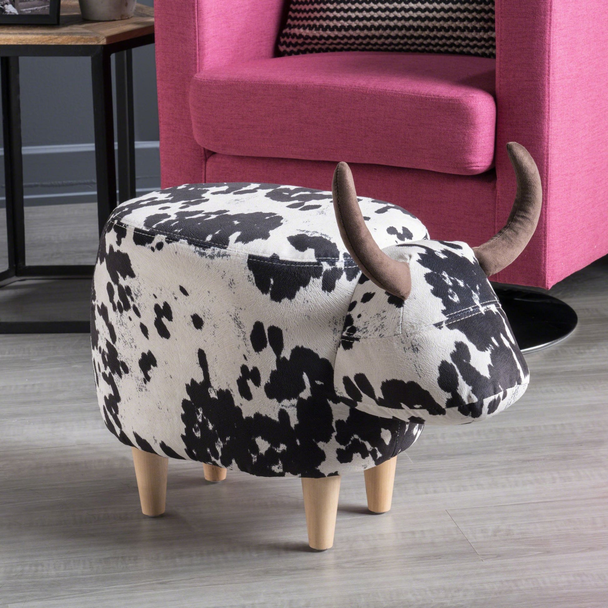 Cow print ottoman with brown horns and four wooden legs