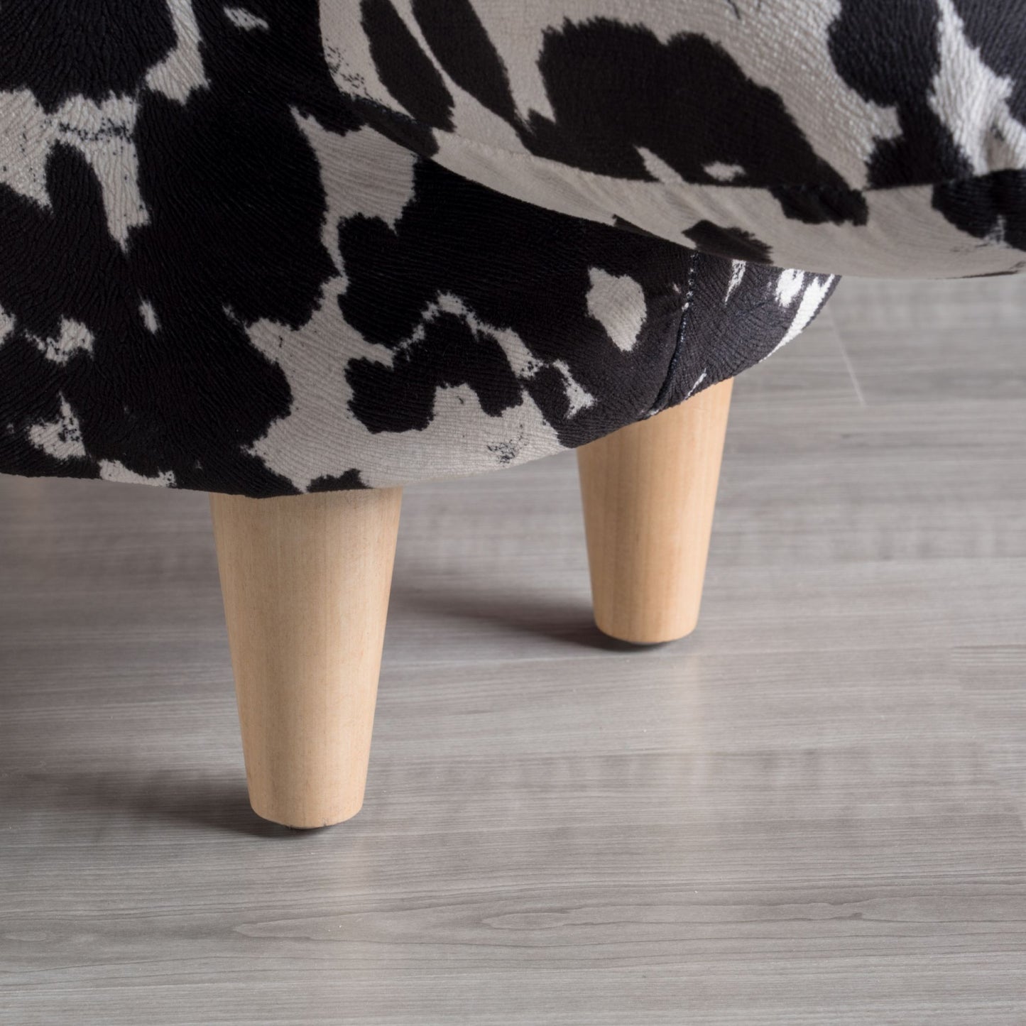 Black and white cow print fabric on a sofa base with wooden legs