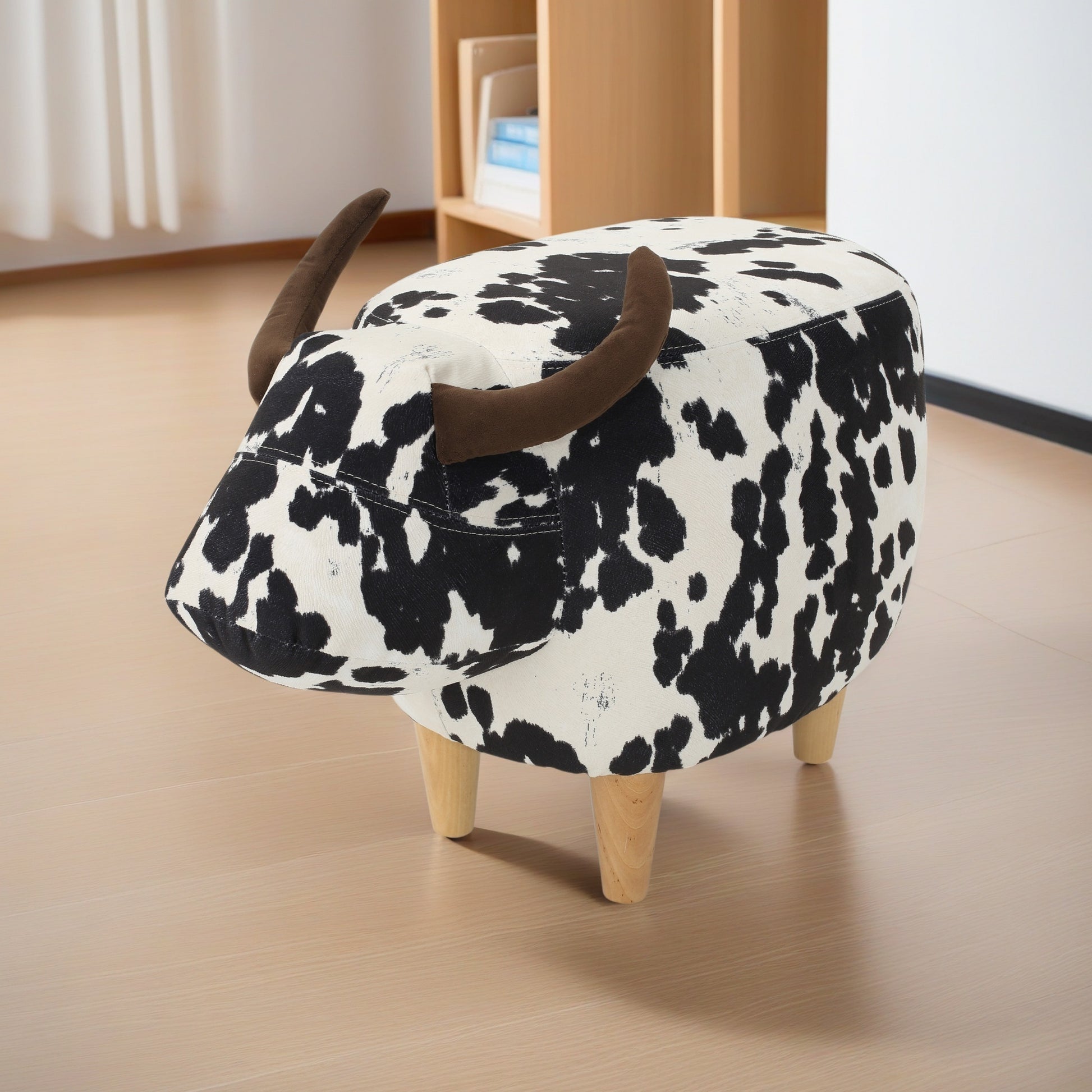 Cow print fabric ottoman with brown horns and wooden legs playful accent seating