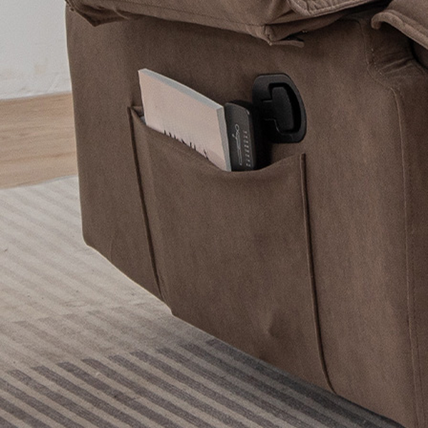 Brown fabric recliner with side pocket holding book and remote control